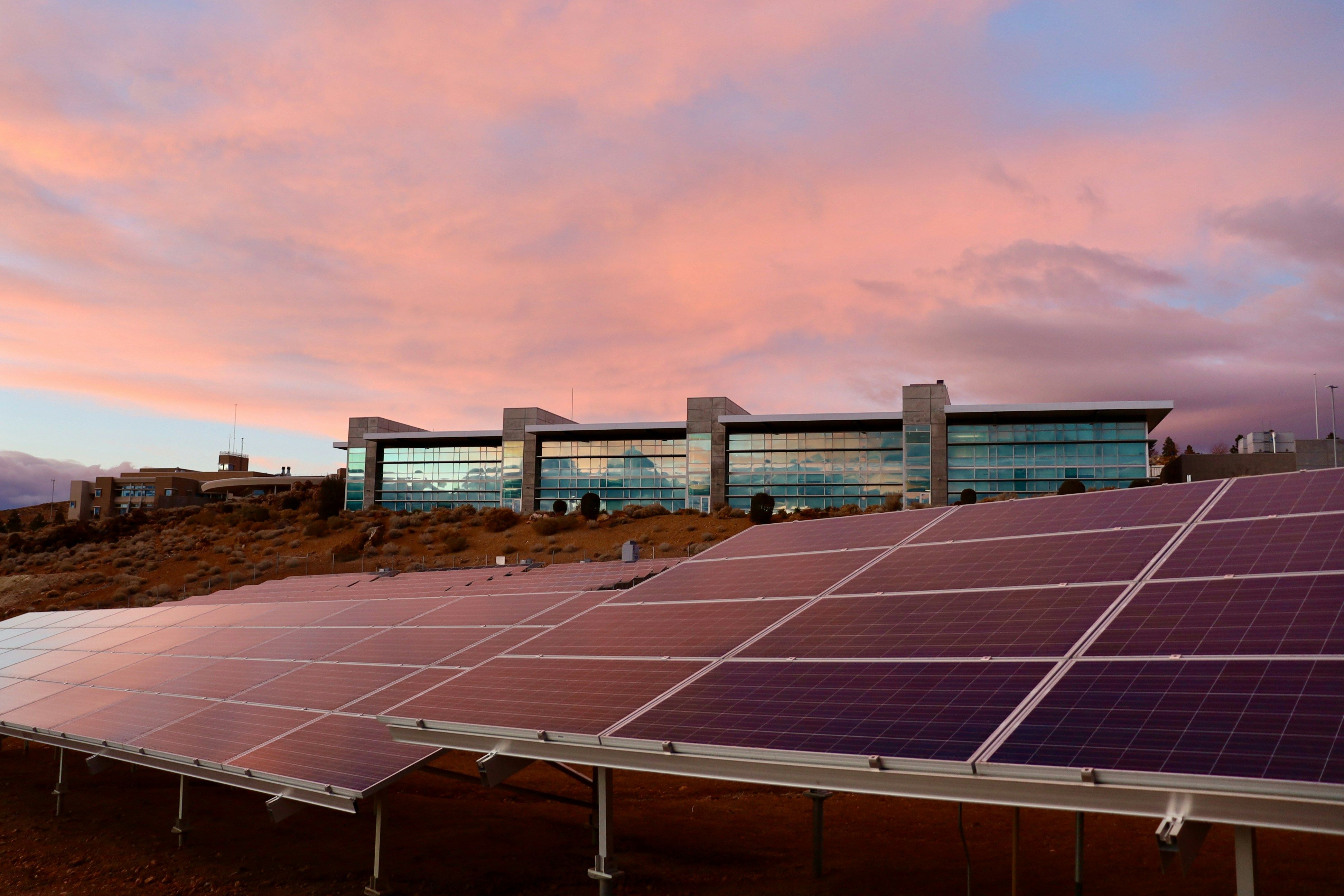 Im Vordergrund sind Solarpanele  im Licht des Sonnenuntergangs